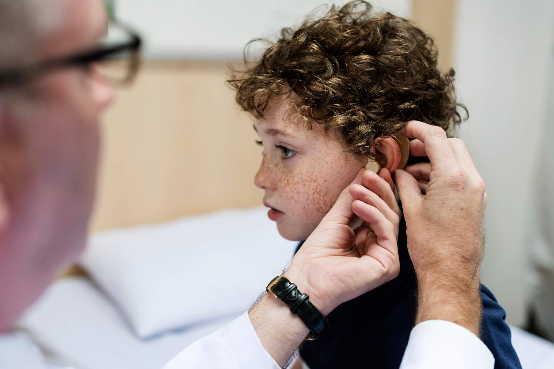 A child gets their hearing aid checked by a doctor